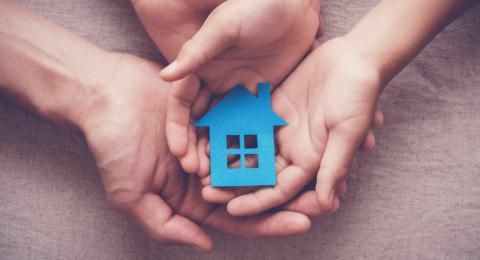 Adult and child hands holding paper house, family home and homeless shelter concept