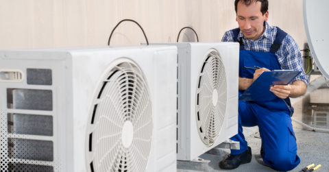 Technician inspecting outdoor HVAC units with a clipboard.