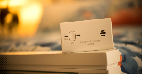 Carbon monoxide alarm placed on a white surface with a blurred background.