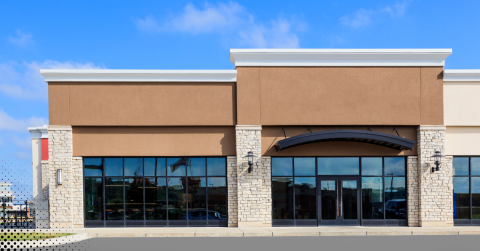 Modern commercial building exterior with large glass windows and stone accents.