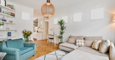Cozy modern living room with beige sectional sofa, blue armchair, wooden floors, and minimalist decor.