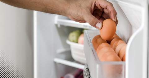 Hand picking an egg from a refrigerator door shelf.