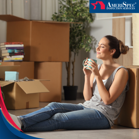 A woman sits on the floor among unpacked moving boxes, holding a mug and enjoying a moment of relaxation.